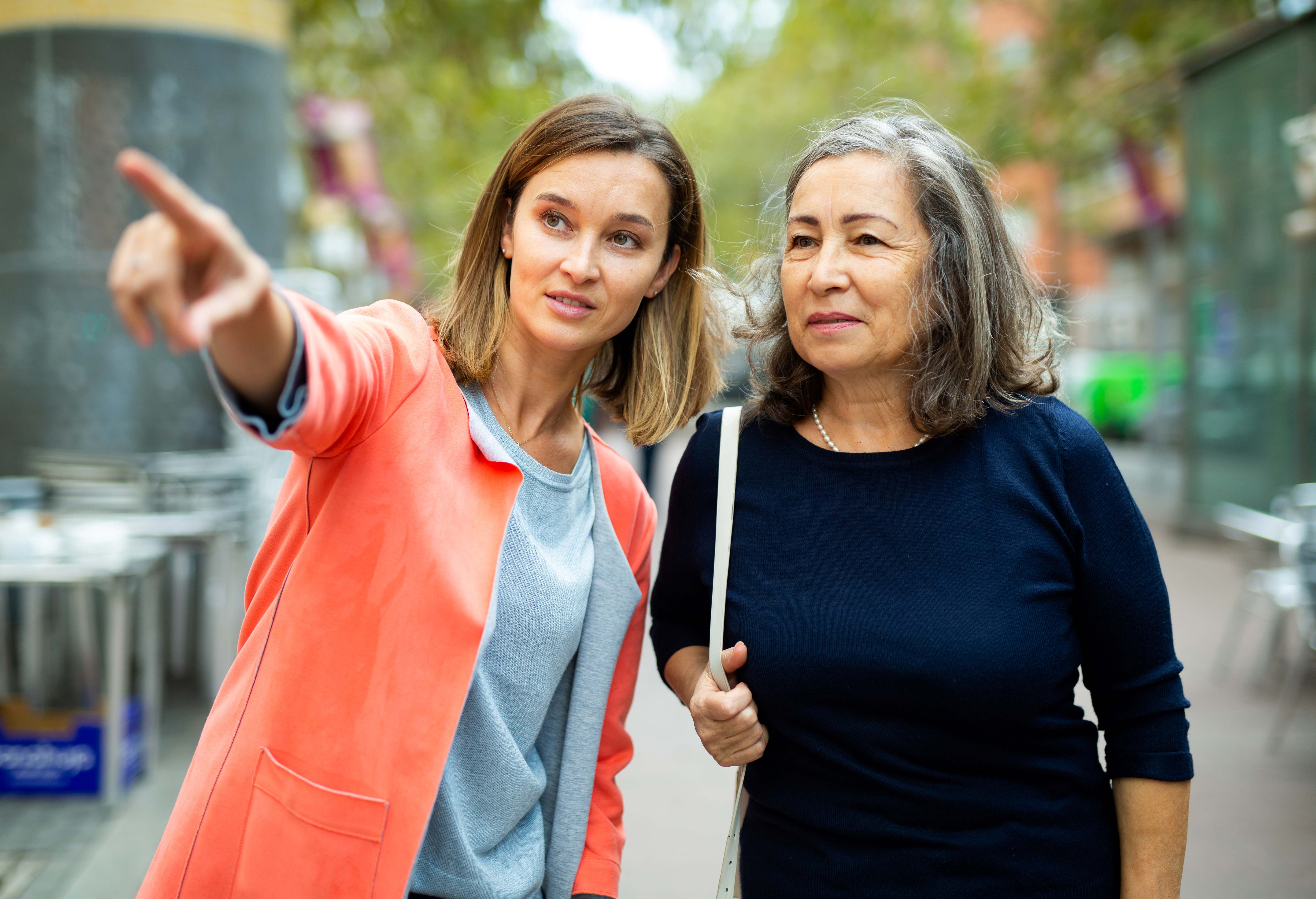 Two women. One is pointing at something.